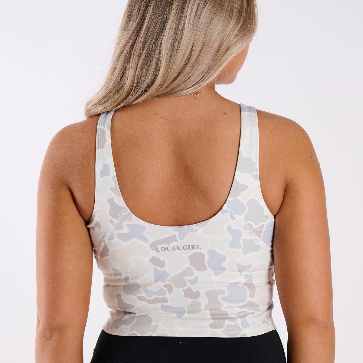 Person wearing a camouflage-patterned tank top with 'LOCAL GIRL' branding on a white background