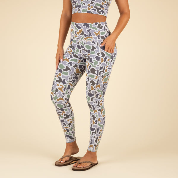 Person wearing camo leggings on a beige background