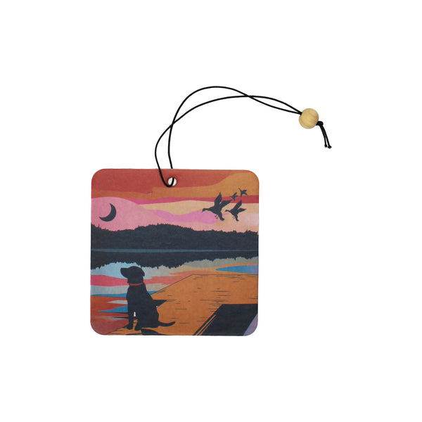 Decorative air freshener with a sunset scene featuring a dog and birds shown on a white background.