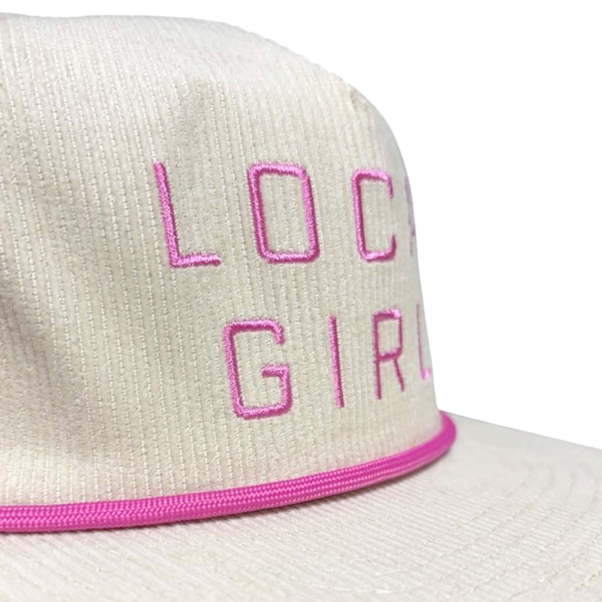 Close-up of Local Girl Outfitters cream corduroy hat with pink embroidered “Local Girl” text and pink rope detail above the brim.