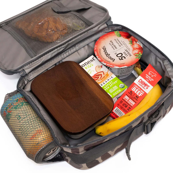 Burlebo lunchbox in classic deer camo opened to show interior contents including a banana, boxed drink, and snack containers.
