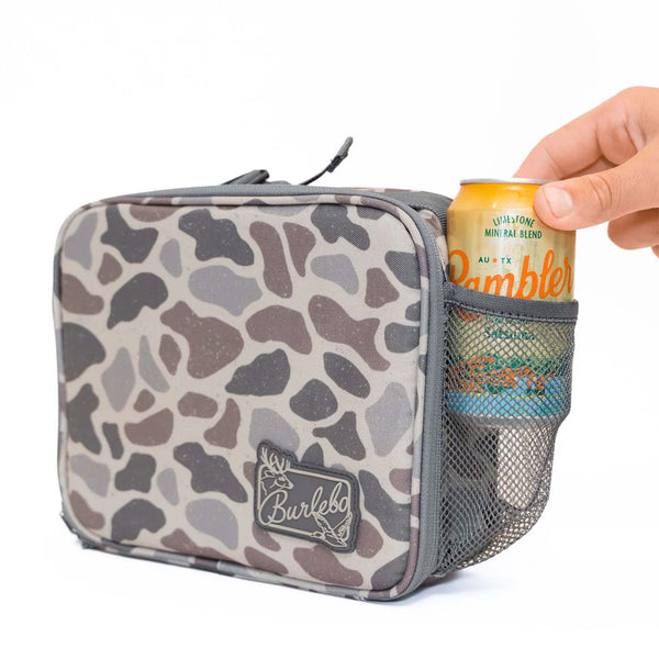 Burlebo lunchbox in classic deer camo with mesh side pocket holding a can of Rambler sparkling water. Camo pattern is a variety of shades of brown and gray.