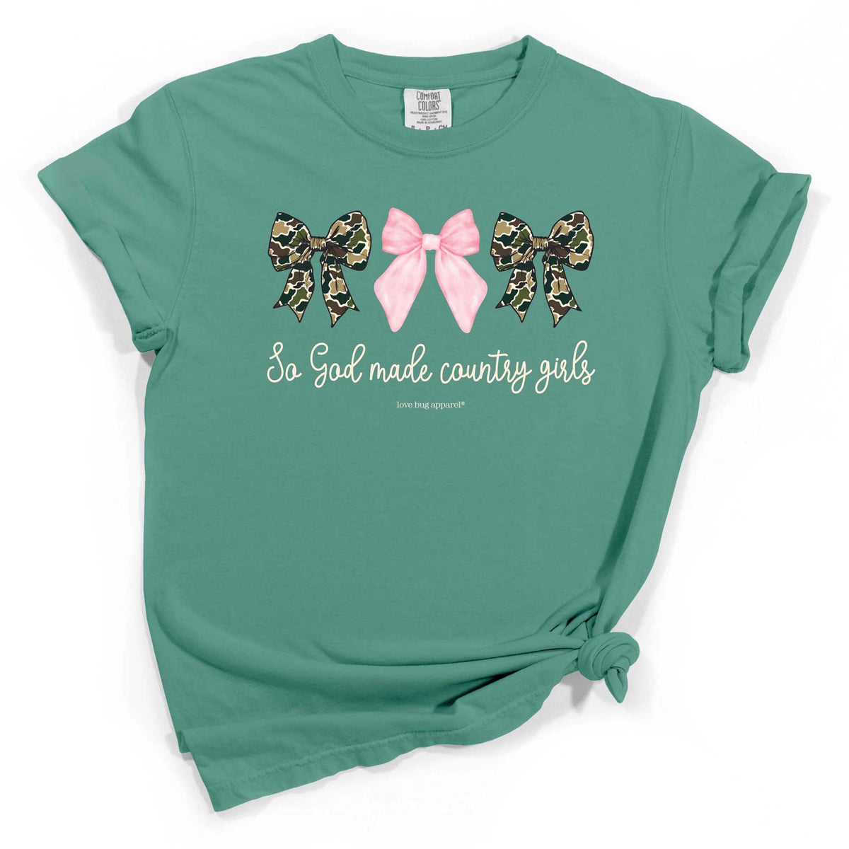 Seafoam green short sleeve t-shirt with three bows across the chest—two camo and one pink—with the phrase “So God made country girls” printed underneath in white script.