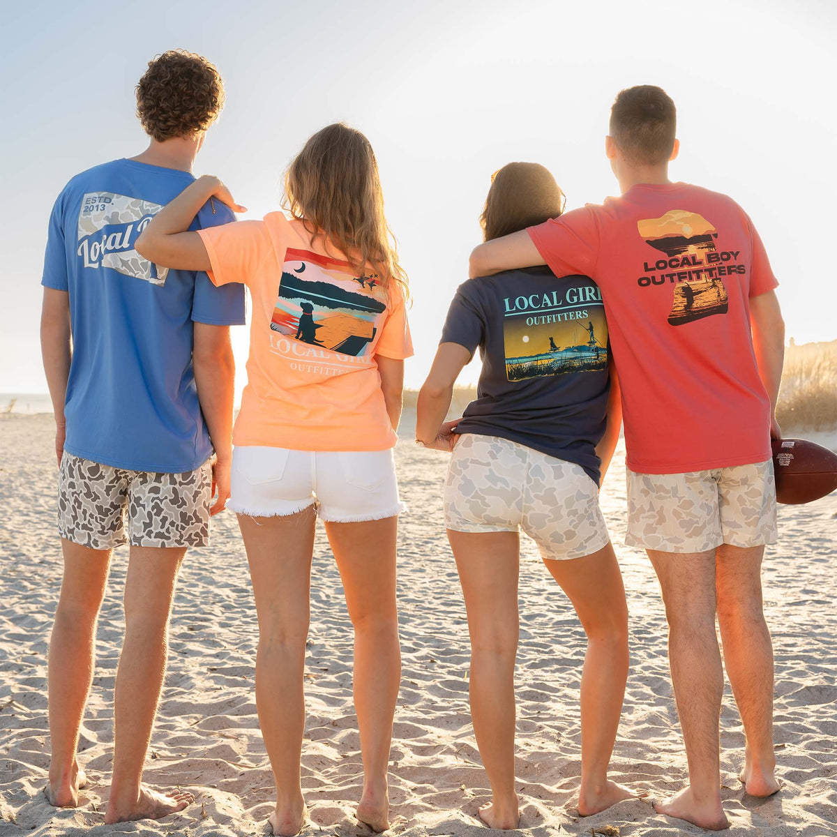 Four people on a beach wearing t-shirts with visible branding.
