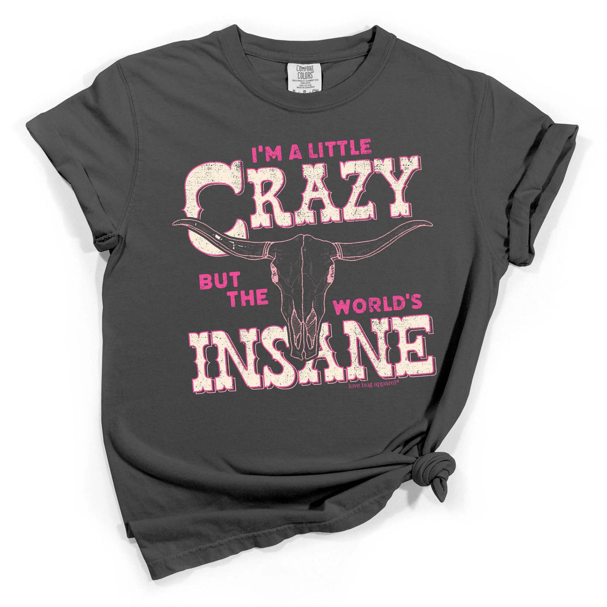 Dark grey short sleeve tee with rolled sleeves featuring pink distressed text and a longhorn skull graphic reading 'I'm a Little Crazy but the World's Insane