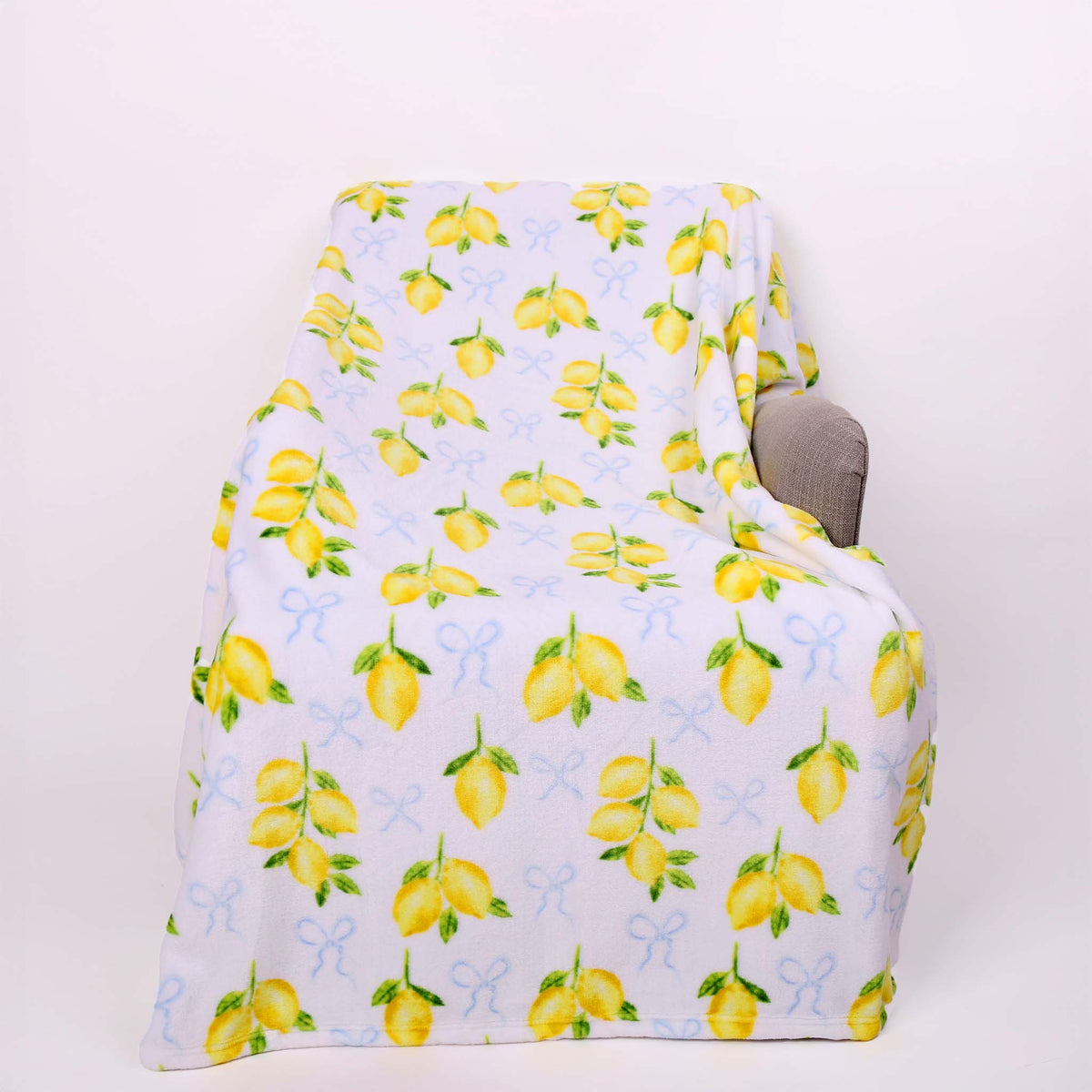 lemon-patterned blanket draped over a chair on a white background