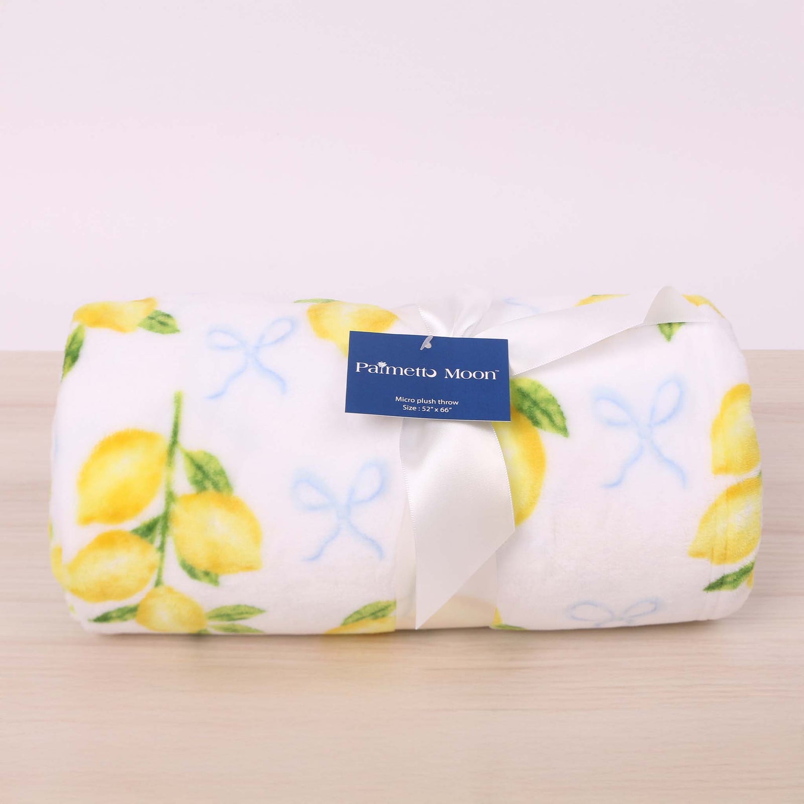 Lemon and bow printed fleece blanket shown rolled up and tied with a bow.
