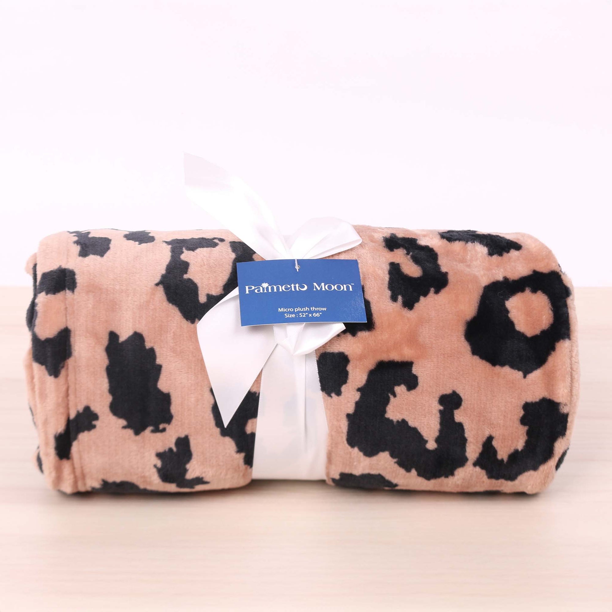 Folded leopard print blanket with a visible brand label on a white background
