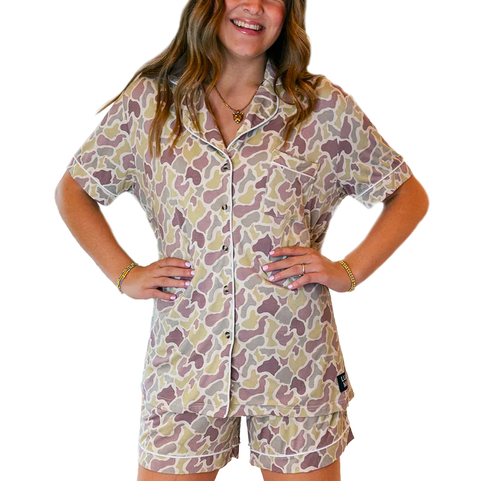 Model wearing Lulu Mac camo pajama set with short sleeve button-front top and matching camo lounge shorts.