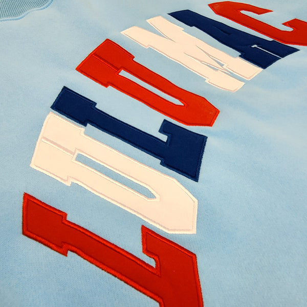 Close-up of the Lulu mac stitched logo on the light blue sweatshirt.