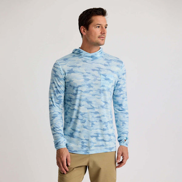Man wearing a long-sleeve hooded shirt in sea smoke blue camo with a chest pocket, shown from the front.