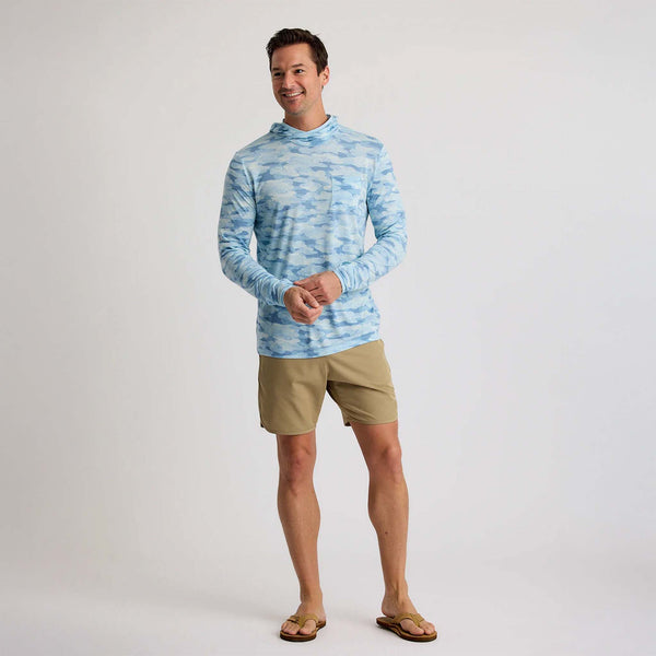 Full-body view of a man in a sea smoke blue camo hoodie and khaki shorts, standing casually.