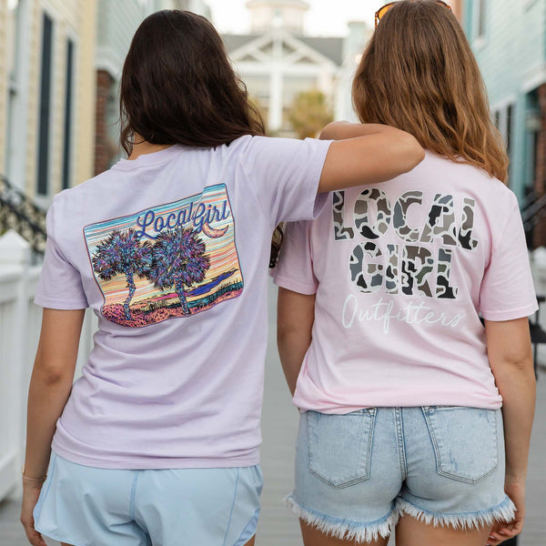 Two people wearing t-shirts with designs on the back, standing close together outdoors.