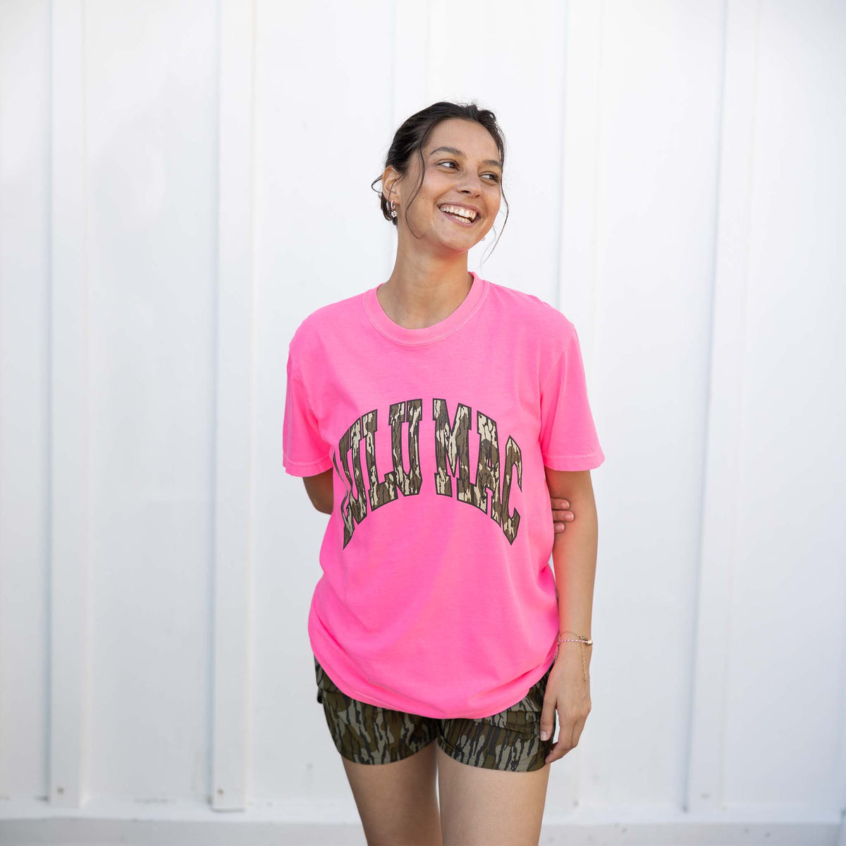 Person wearing a bright pink t-shirt with text, standing against a white background