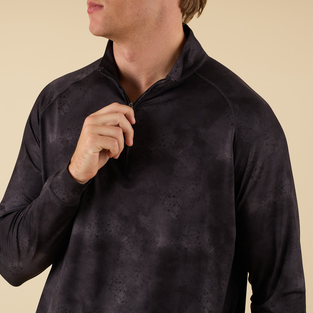 Close-up of COAST Apparel men’s black camo quarter-zip showing zip collar detail.