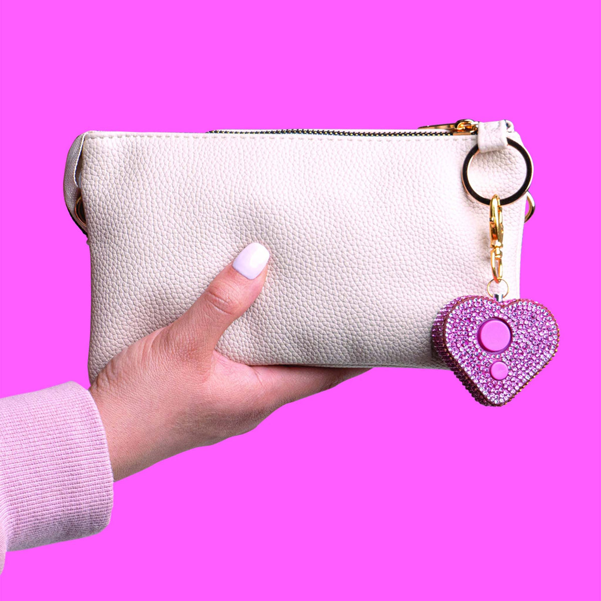 White clutch bag with a pink heart-shaped keychain on a pink background