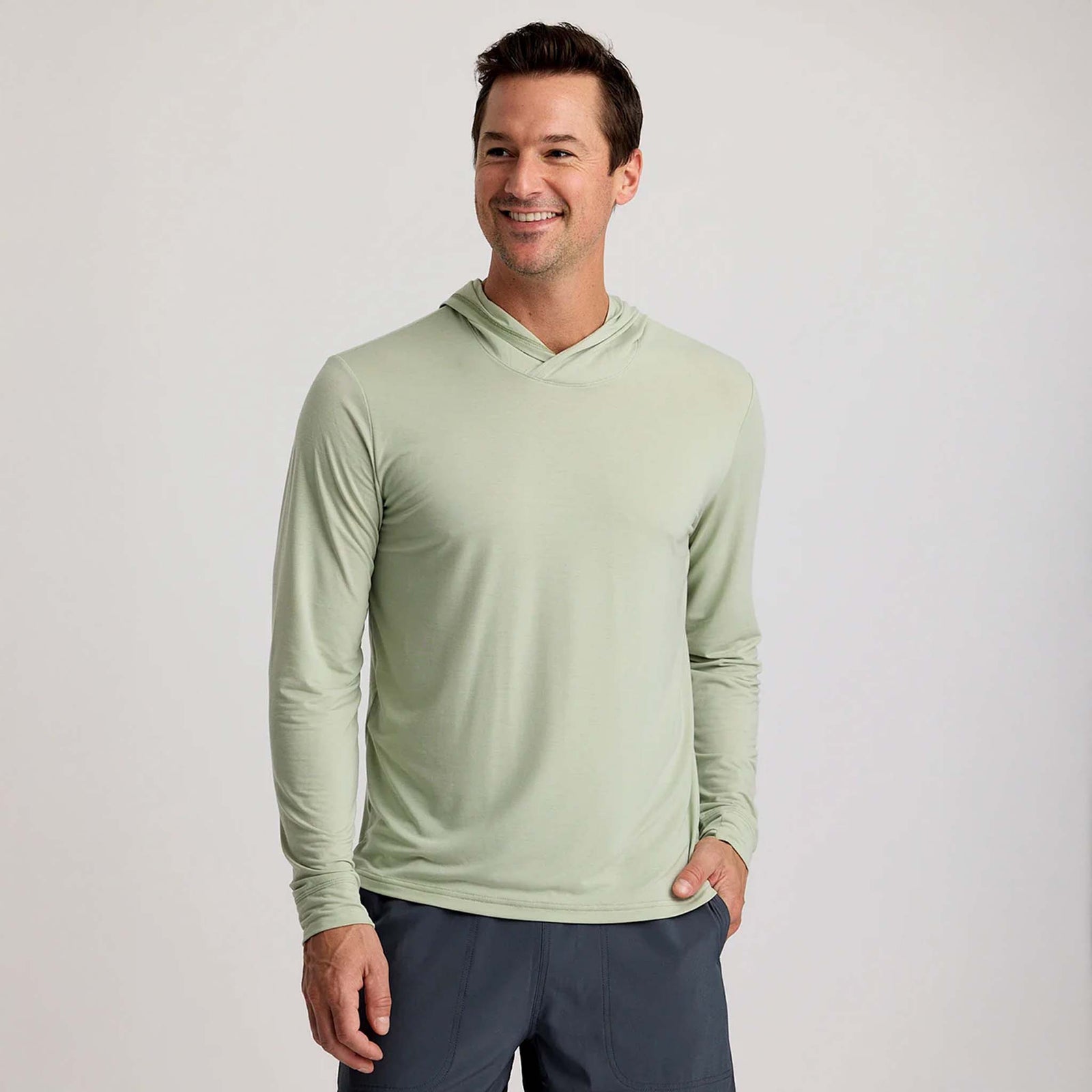Man smiling in a Desert Sage green long sleeve hooded shirt with crossover neckline and no visible logos.