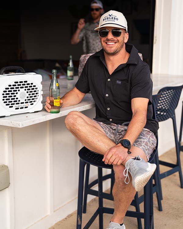 man sitting at an outdoor poolside bar posing for a picture