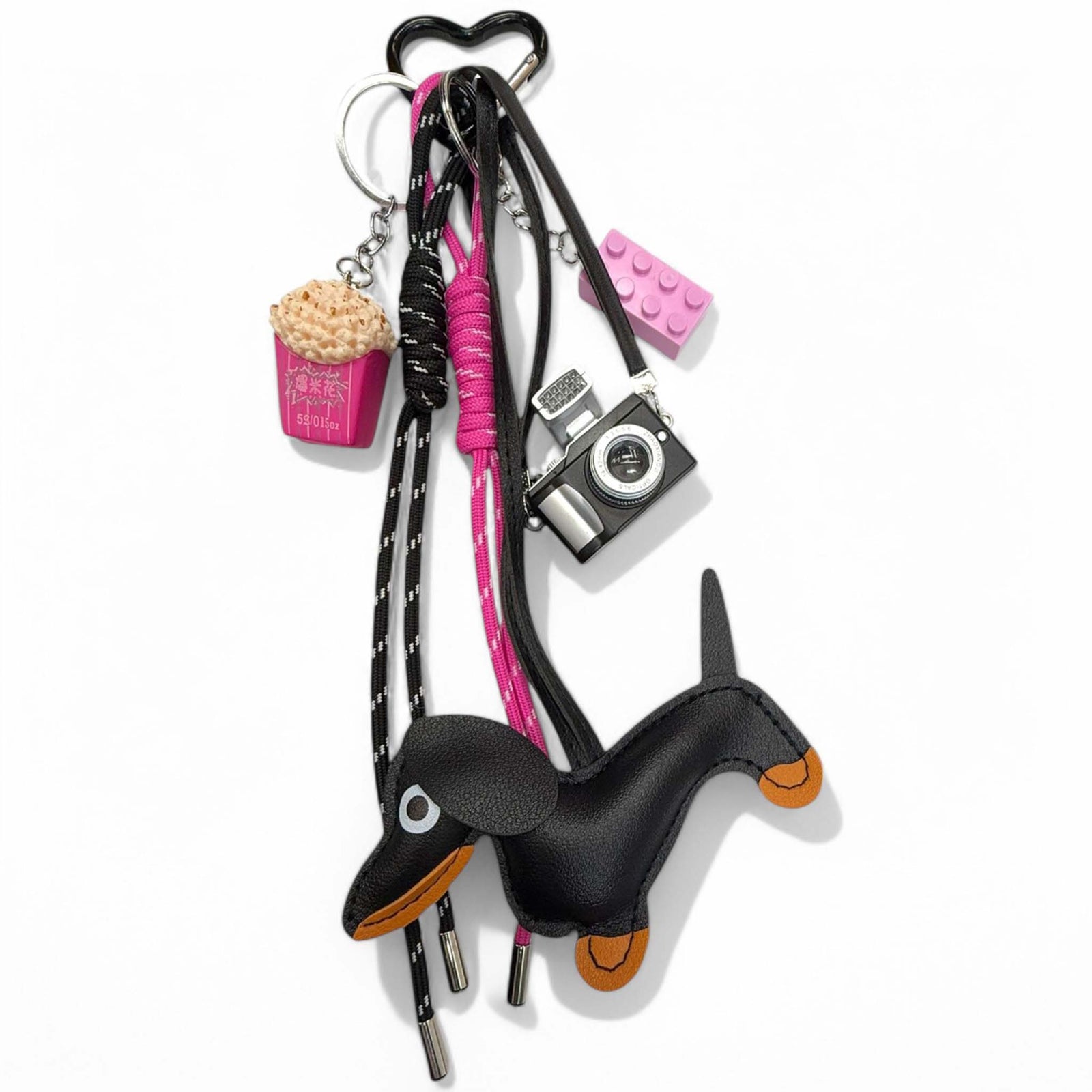 Purse charm shaped like a wiener dog, featuring a long body, short legs, and detailed facial features, made of faux leather with a metal clip for easy attachment.