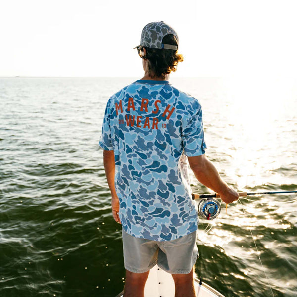 Man standing on a boat wearing the Stackhouse Tech Short Sleeve T-Shirt in silver mallard camo from Marsh wear. He has a fishing pole in his right hand.