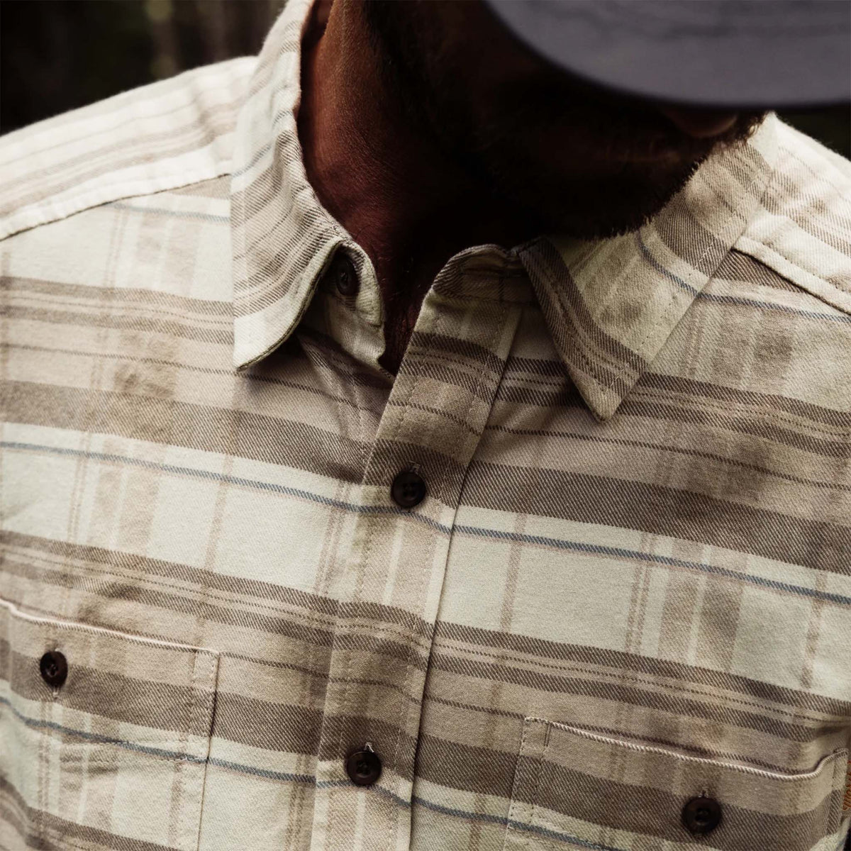 Close-up of a person wearing a plaid shirt with a blurred background
