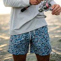 Men’s blue and gray camo swim trunks with drawstring waistband, shown in close-up while fishing at the beach.