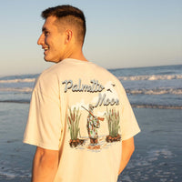 Man wearing a t-shirt with 'Palmetto Moon' design on the beach