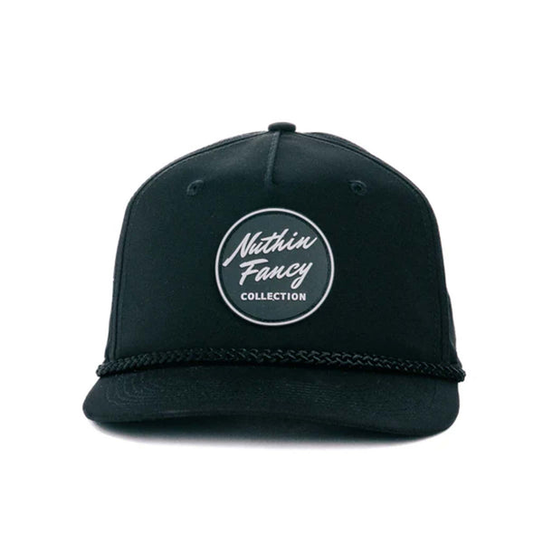 Black performance trucker hat made from moisture-wicking fabric, featuring laser perforated side and back panels for breathability. Includes a white-accented rubber 'Nuthin’ Fancy' patch on the front, a stylish black rope detail above the pre-curved bill, and an adjustable plastic snapback closure. One size fits most (58 cm).