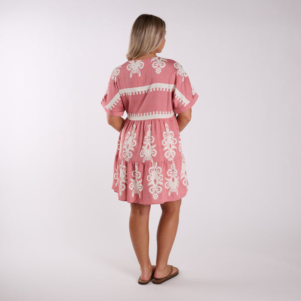  Woman wearing a pink dress with white embroidery on a white background