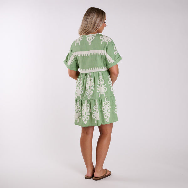  Woman wearing a green dress with white floral patterns on a white background