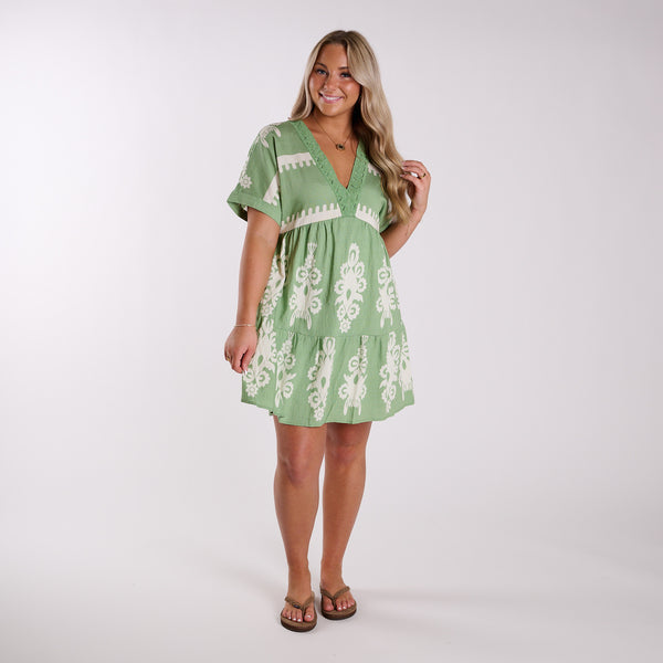  Woman wearing a green dress with white embroidery on a white background