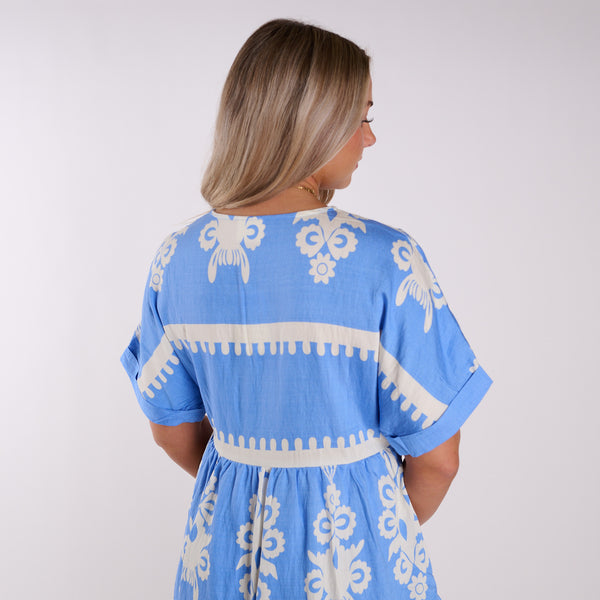  Woman wearing a blue dress with white patterns on a plain background