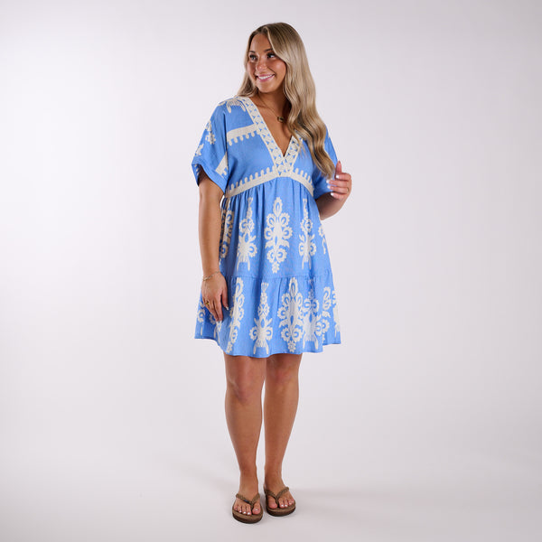  Woman wearing a blue dress with white embroidery on a white background