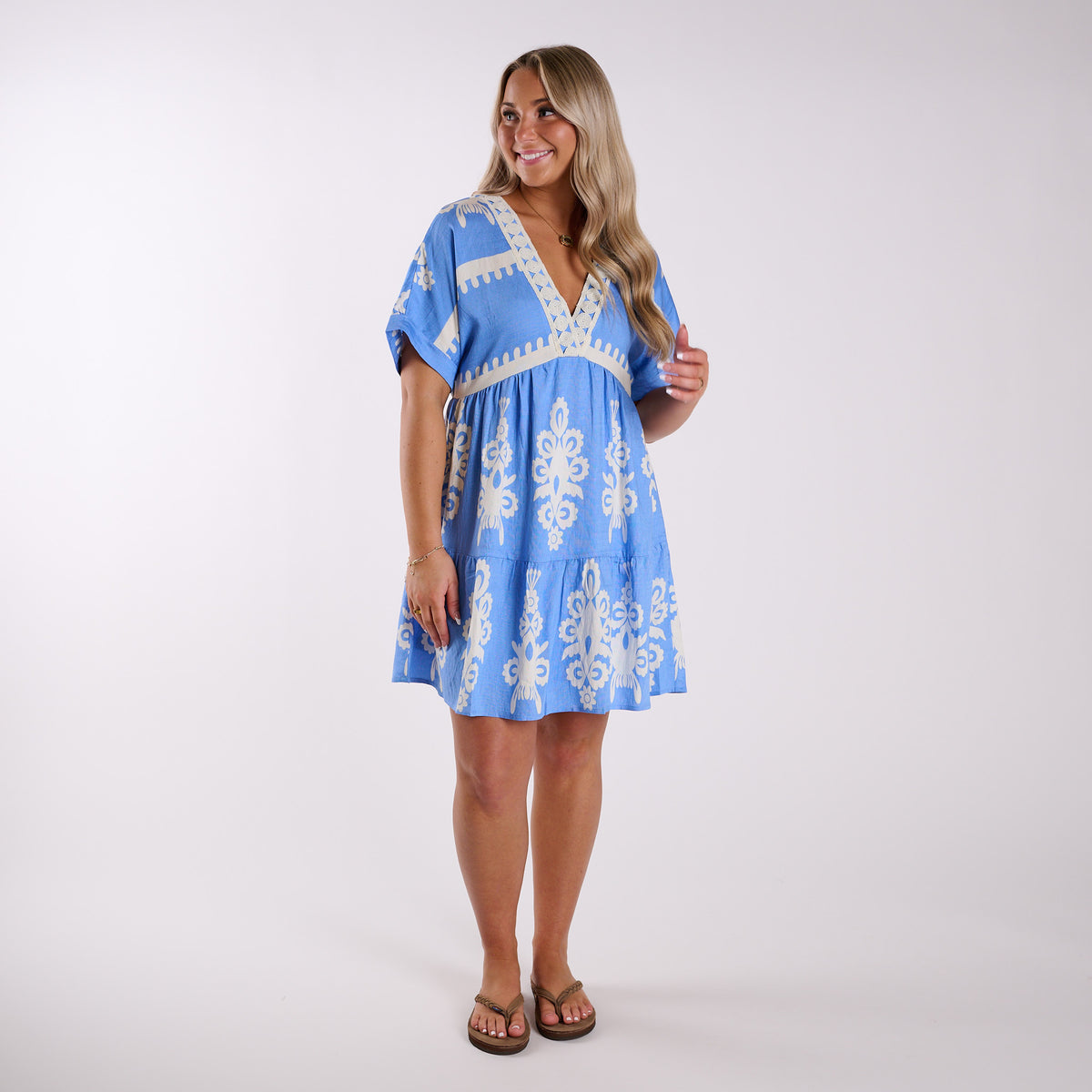 Sky | Woman wearing a blue dress with white embroidery on a white background