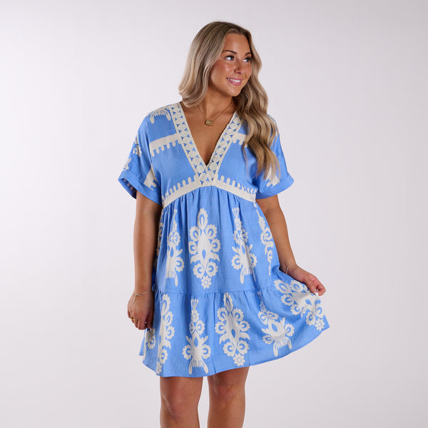  Woman wearing a blue dress with white patterns on a white background