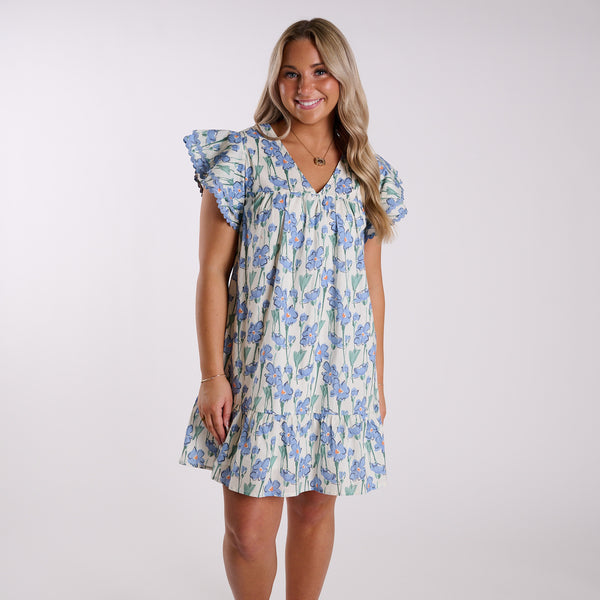  Woman wearing a blue floral dress on a grey background.