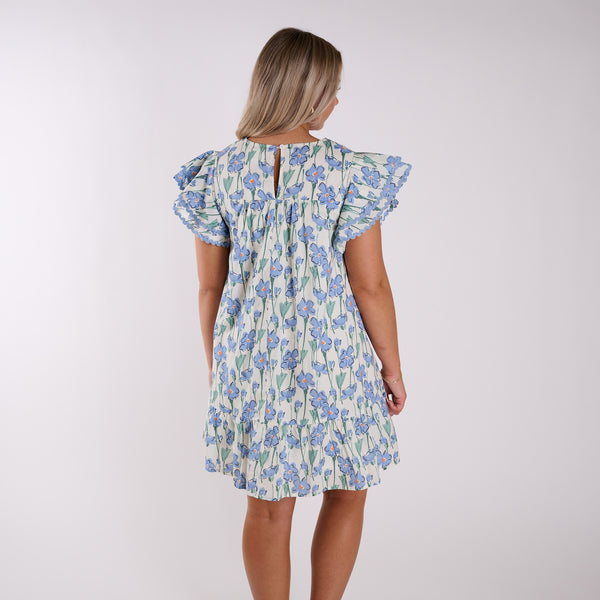  Back view of a woman wearing a blue floral dress.