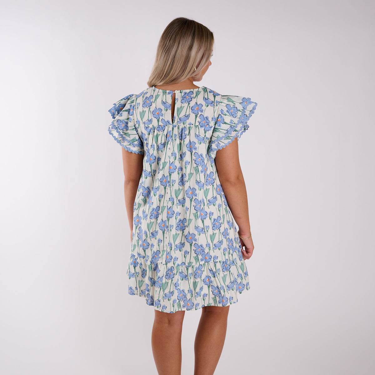 Back view of a woman wearing a blue floral dress.
