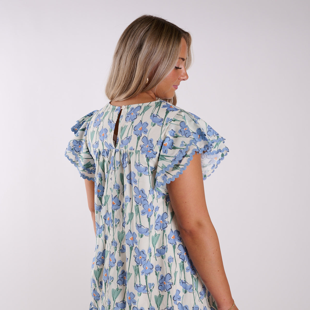 Close up back view of a woman wearing a blue floral dress.