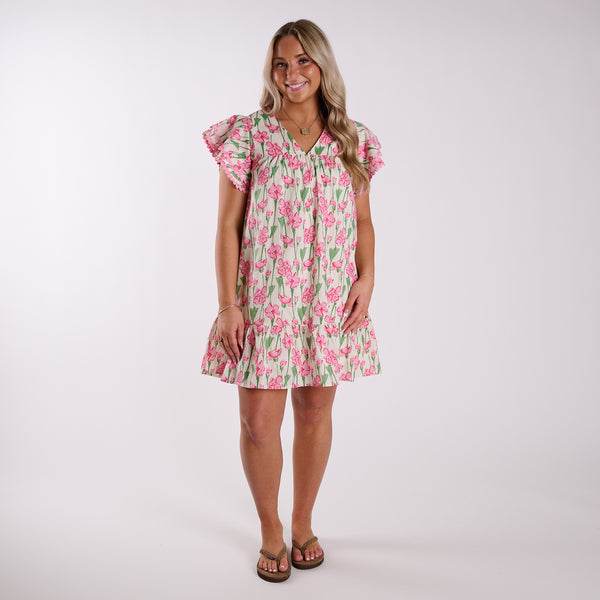  Woman wearing a pink floral mini dress on a plain background.