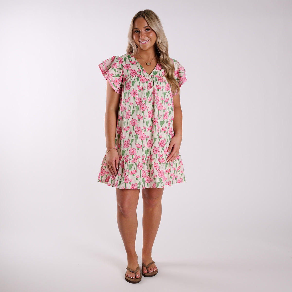 Woman wearing a pink floral mini dress on a plain background.