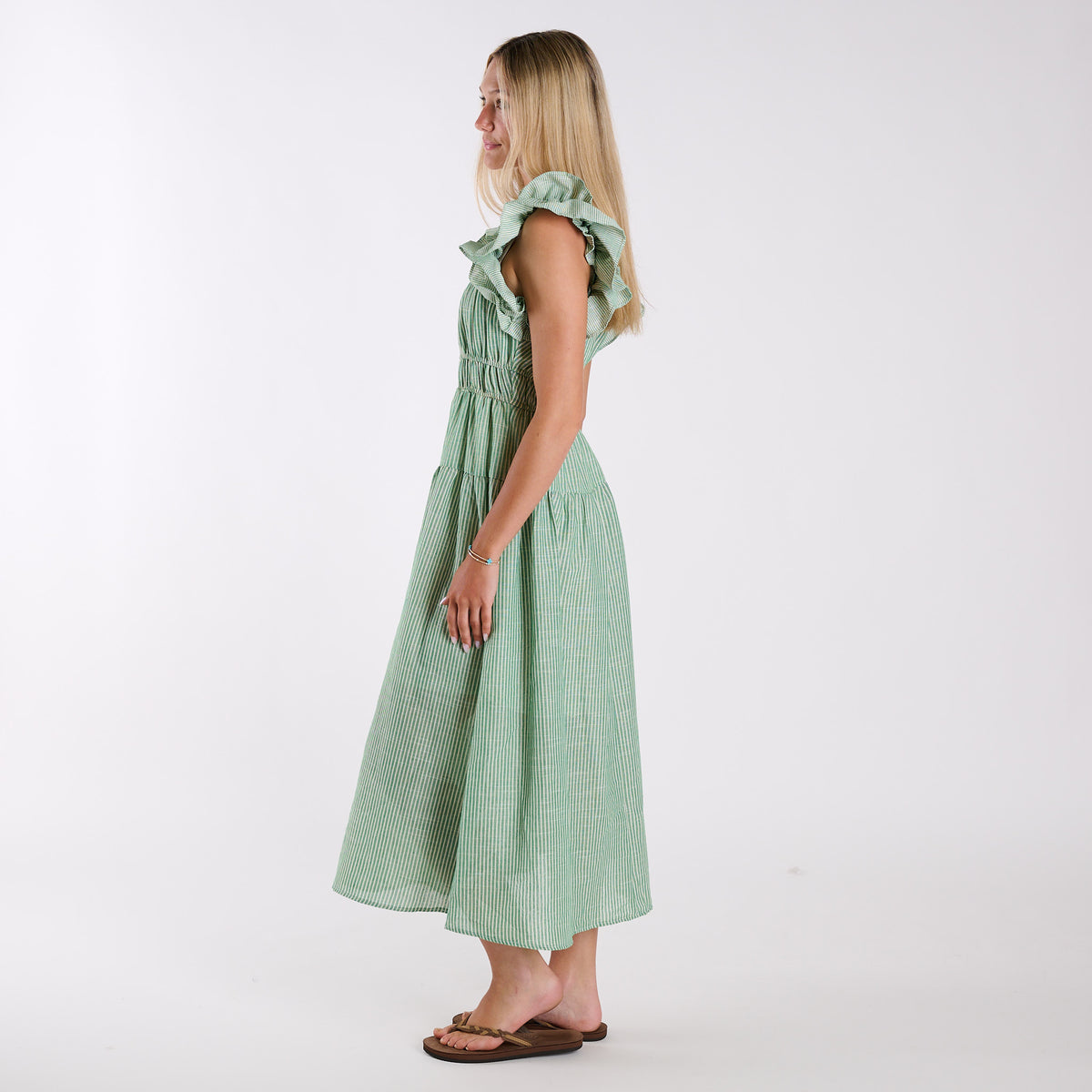 Green| Green stripe seersucker maxi dress with ruffle shoulder straps and smocked waistband, shown in side profile.