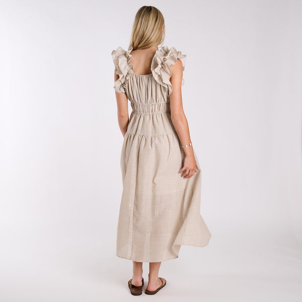  Woman wearing a beige dress with ruffled sleeves on a white background
