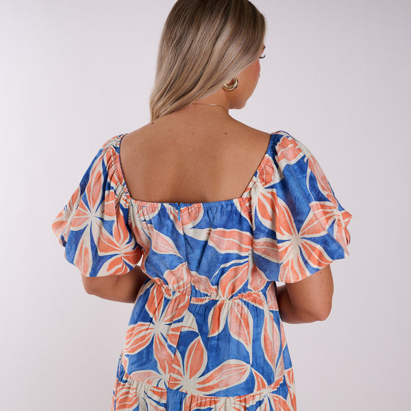 Back view of a Woman wearing a colorful floral dress on a white background