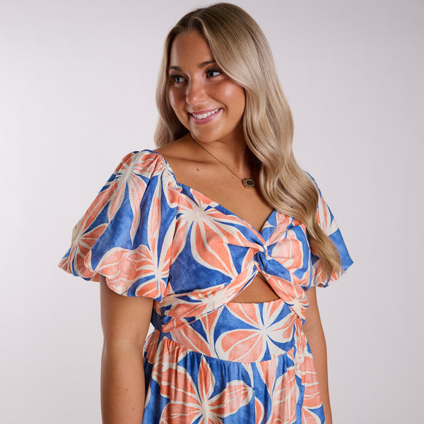 Woman wearing a colorful floral dress against a plain background
