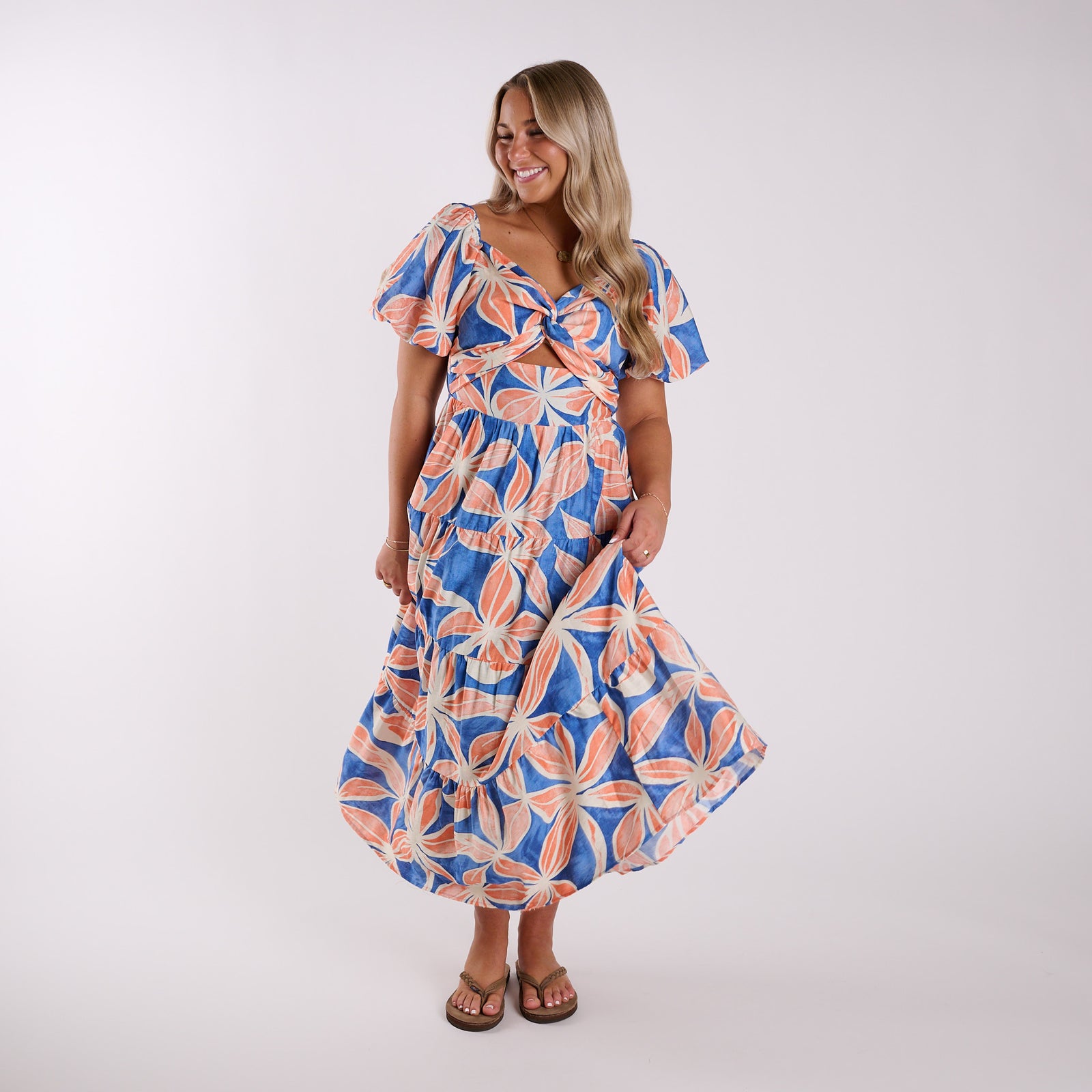Woman wearing a blue and orange floral dress on a white background