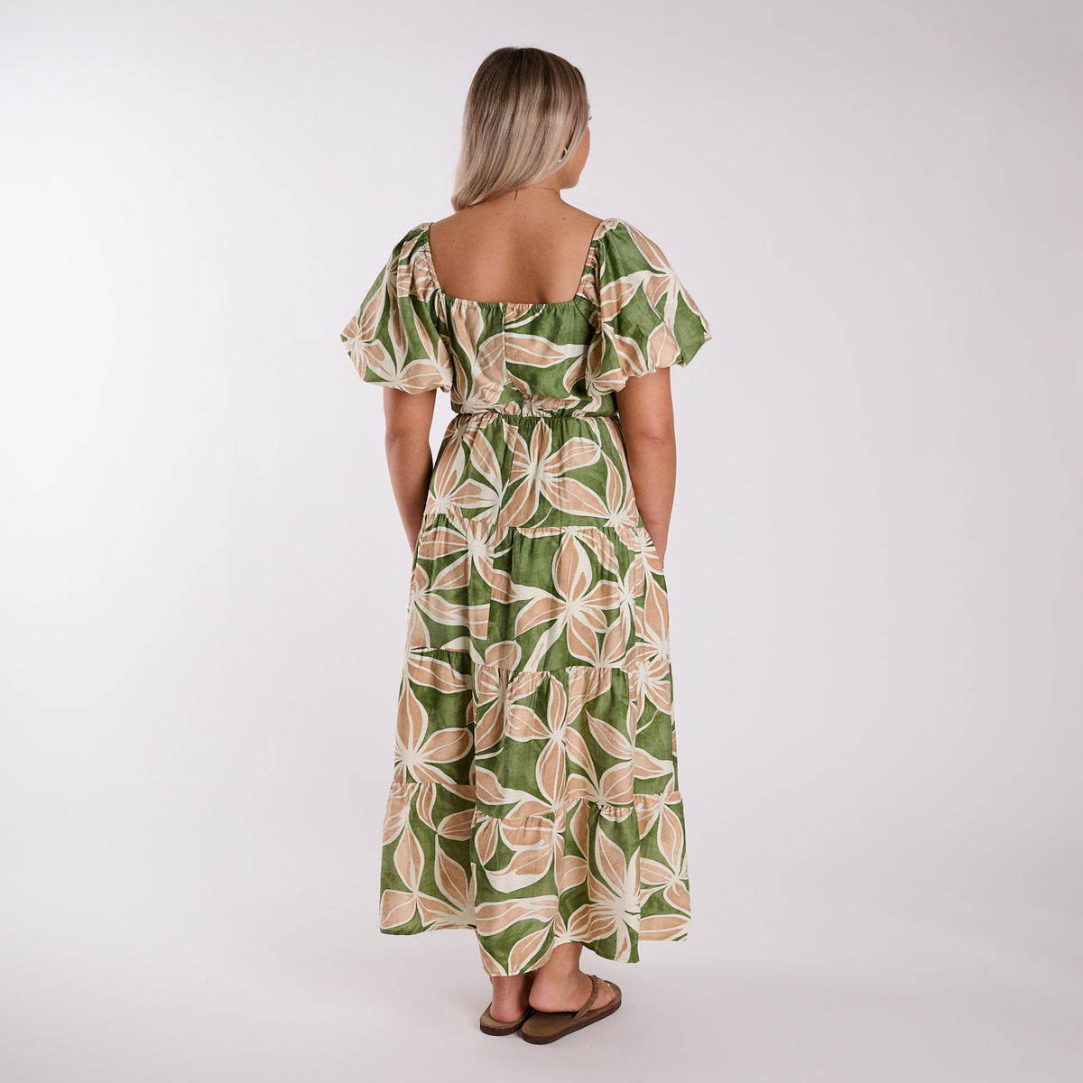 Woman wearing a green and beige floral dress on a white background