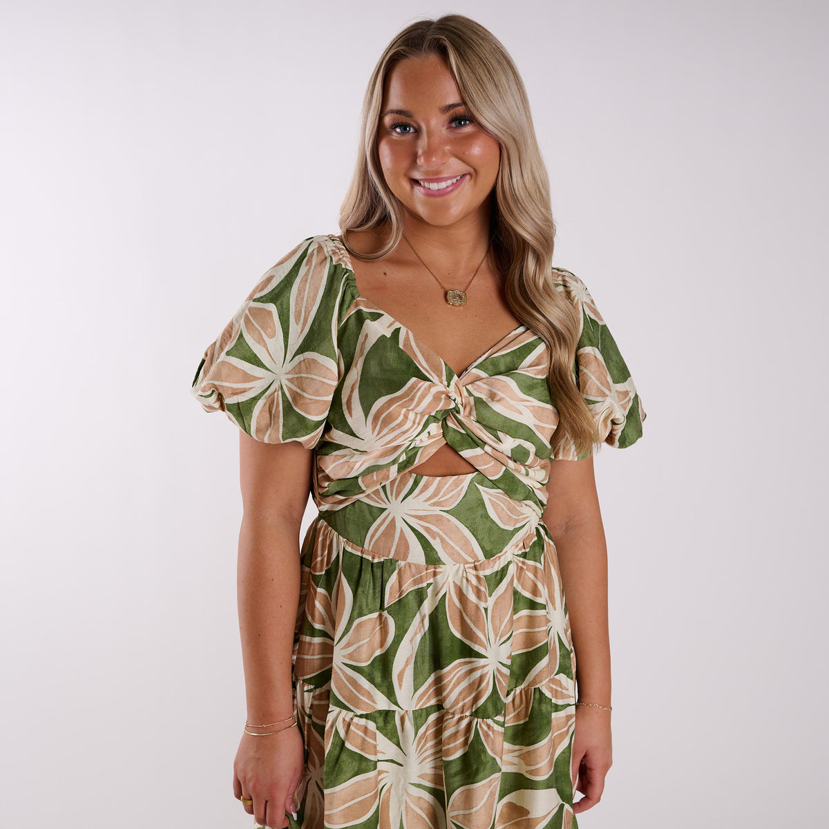 Woman wearing a green and beige floral dress on a white background