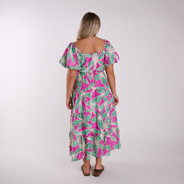 Woman wearing a pink and green floral dress on a white background