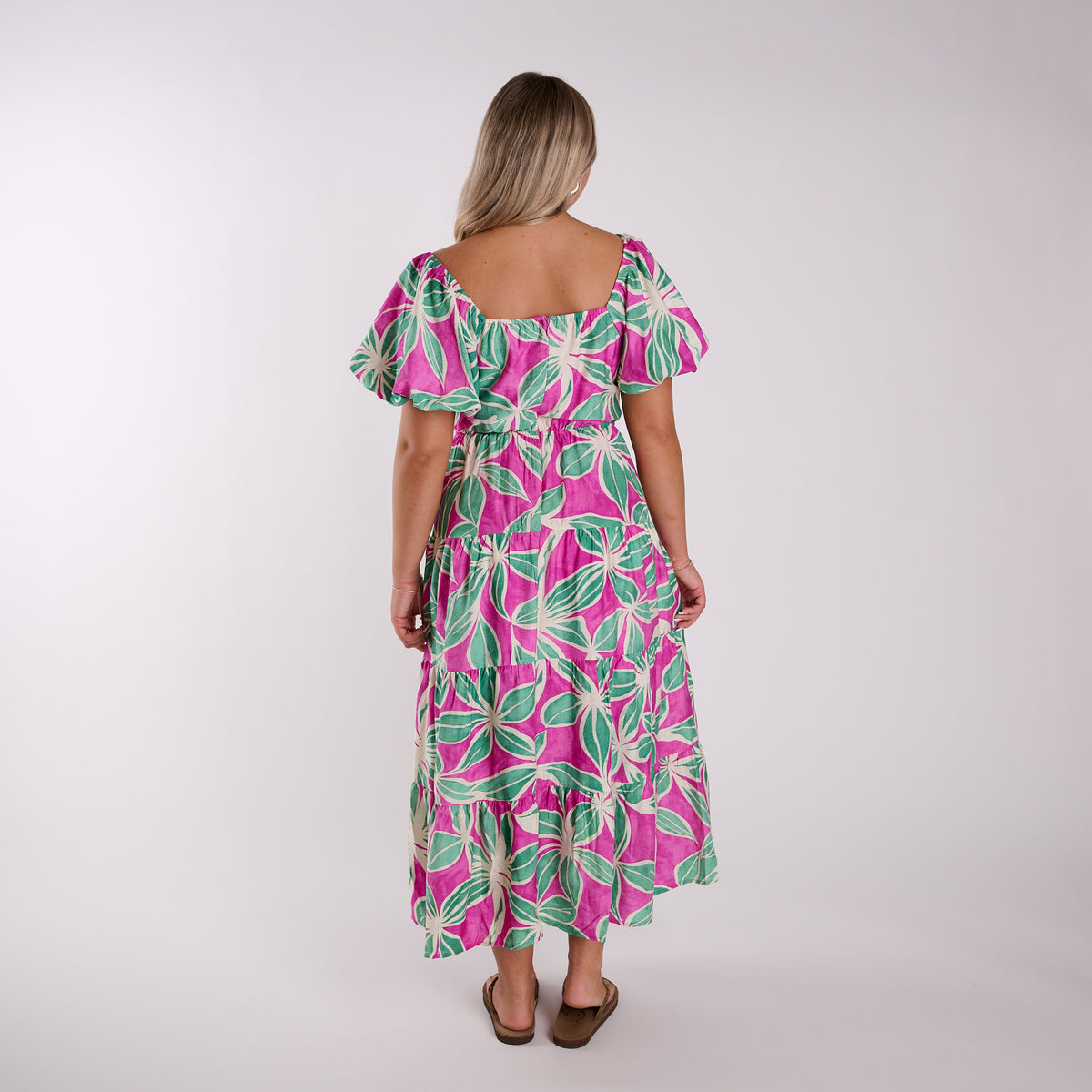 Woman wearing a pink and green floral dress on a white background